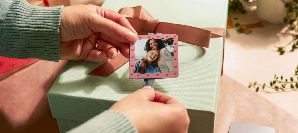 Quadratischer Magnet mit Foto von zwei Freundinnen und Herzrand wird an einem Geschenkband befestigt