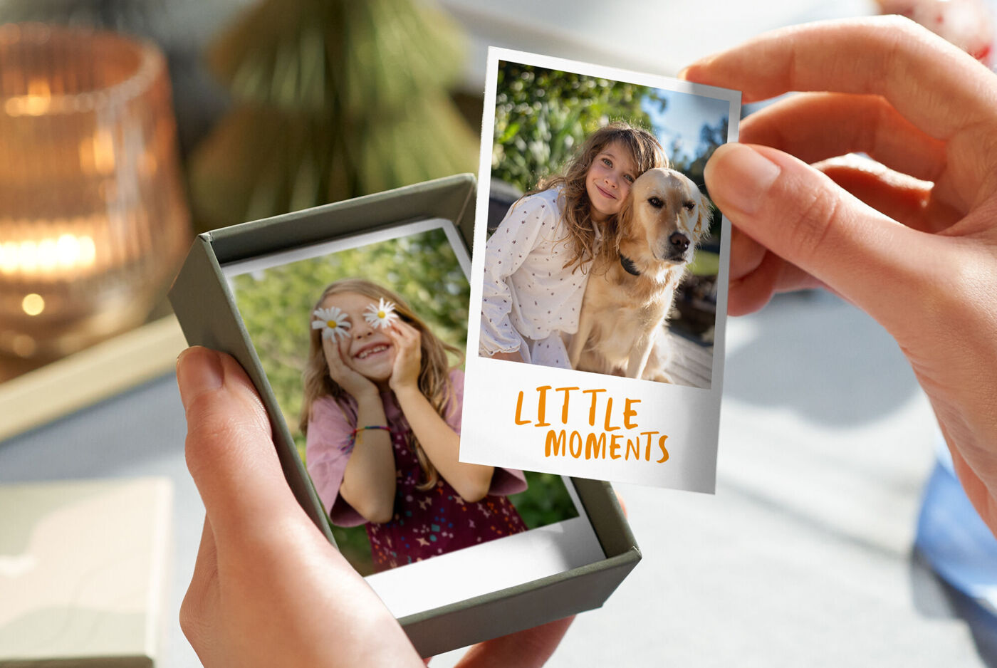 Eine Hand hält eine geöffnete Box, in der kleine Fotoabzüge von Kindern und einem Hund mit weißem Rand zu sehen sind