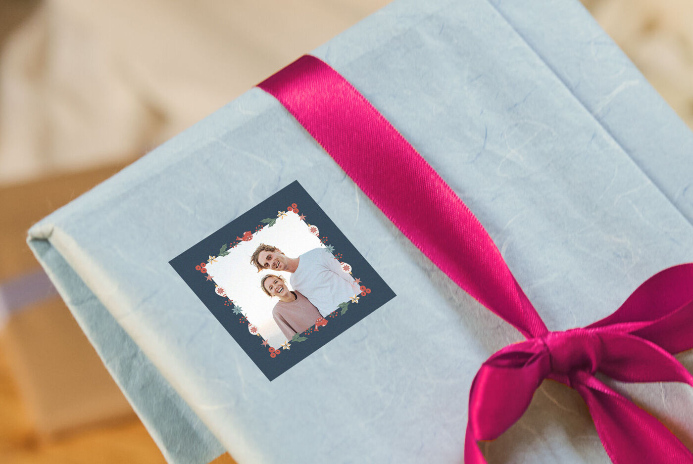 Ein Fotosticker, auf dem ein Paar abgebildet ist, ist auf ein Geschenk mit roter Schleife geklebt