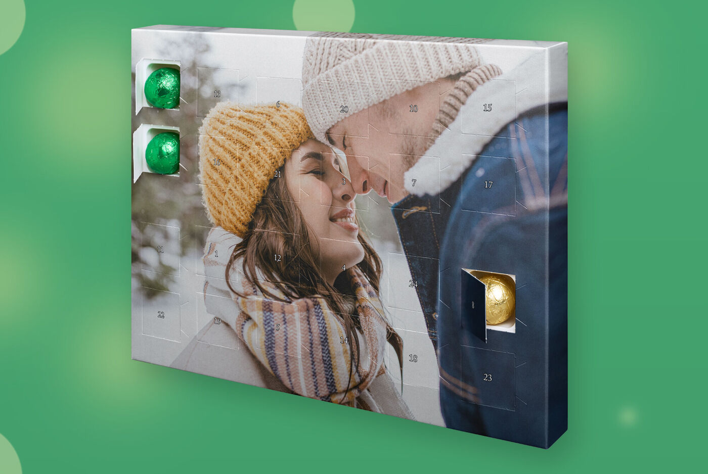 Adventskalender mit großem Foto, zwei Personen in Winterkleidung, mehrere Türchen offen mit Schokokugeln