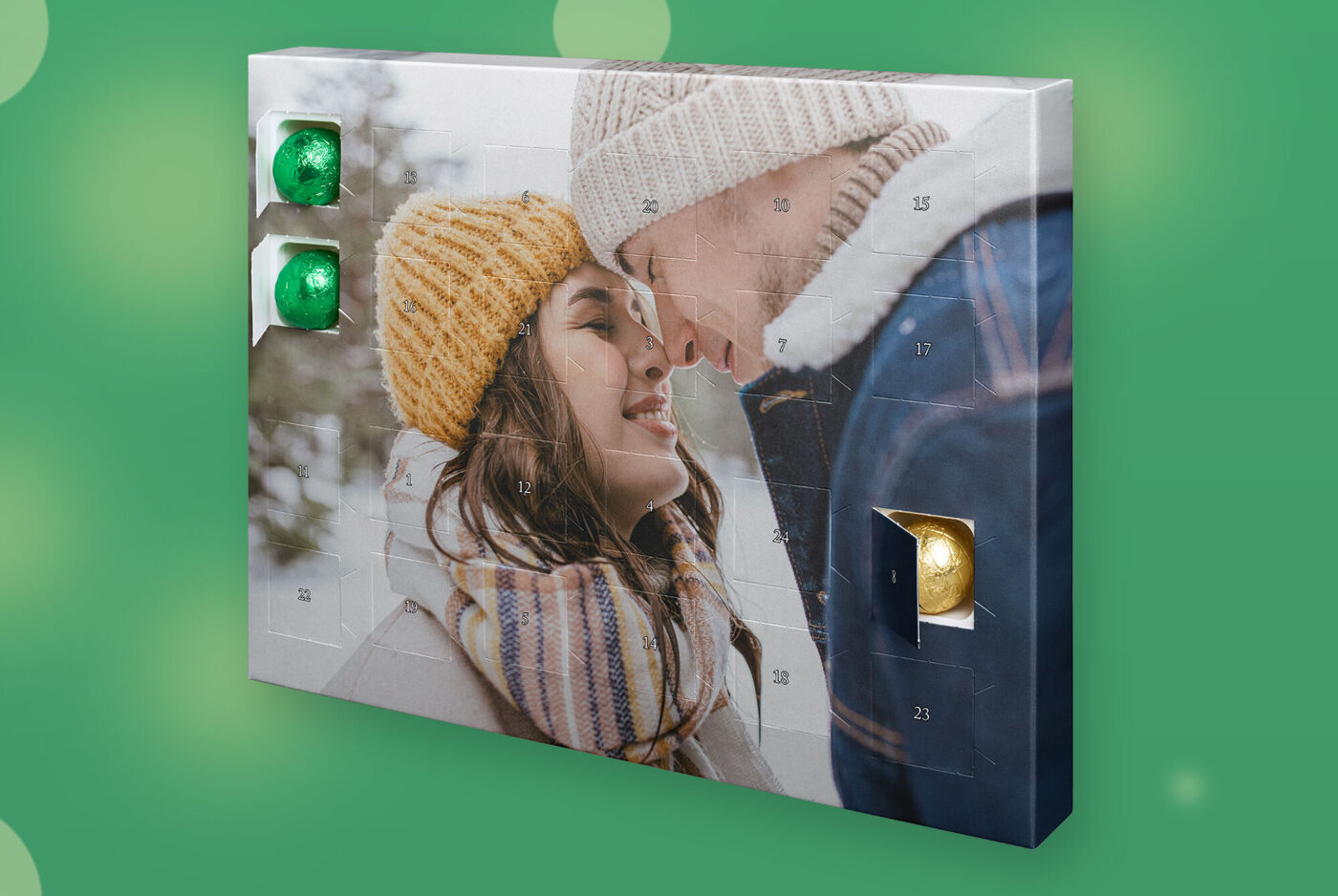 Adventskalender mit großem Foto, zwei Personen in Winterkleidung, mehrere Türchen offen mit Schokokugeln
