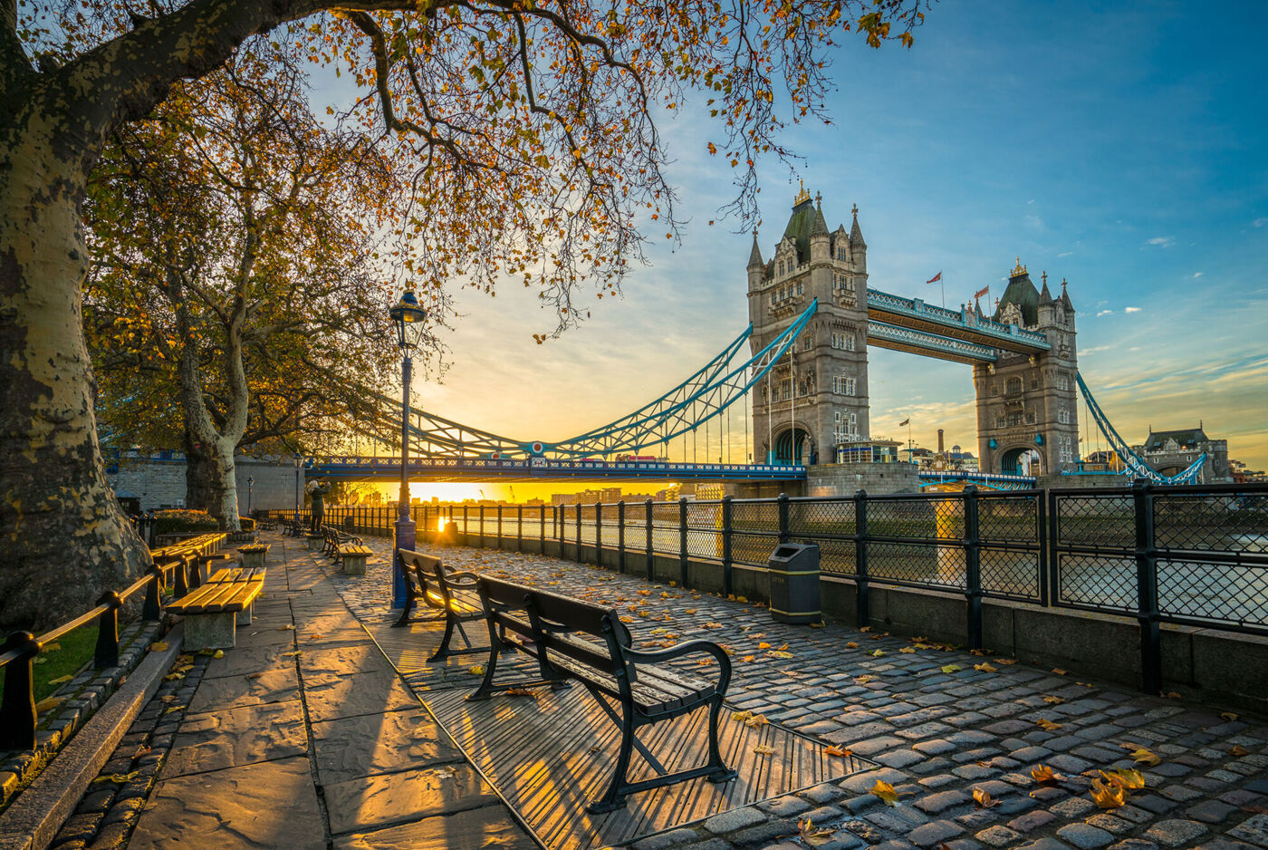 Vorne stehen in mehrere Sitzbänke mit Sicht auf die Tower Bridge im Hintergrund.